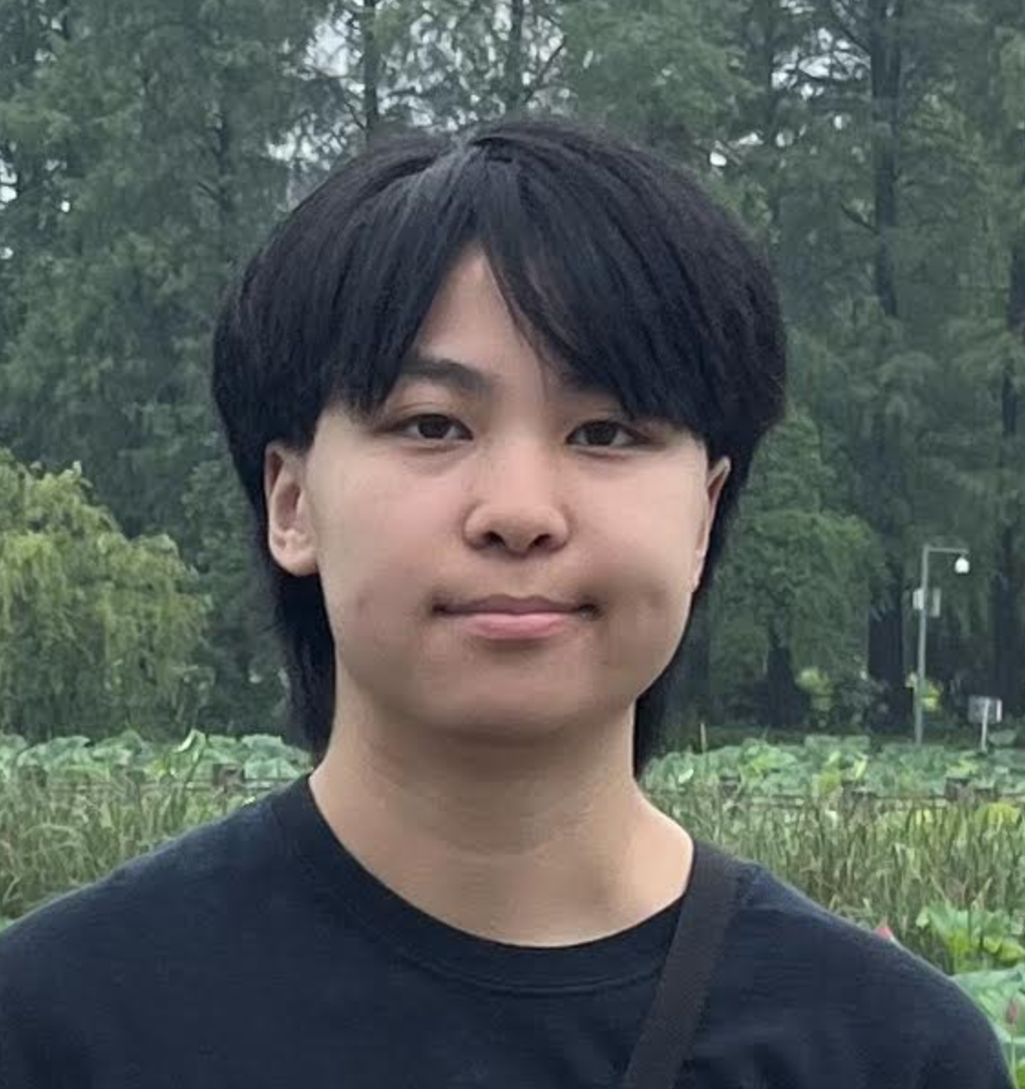 Sarina staring at the camera and smiling in a black shirt in nature