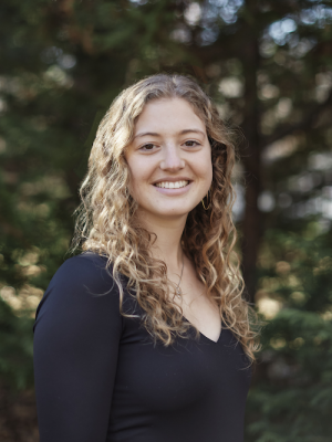 Karoline Trovato headshot against dark forest background