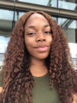 Black girl smiling with curly brown hair and olive color shirt